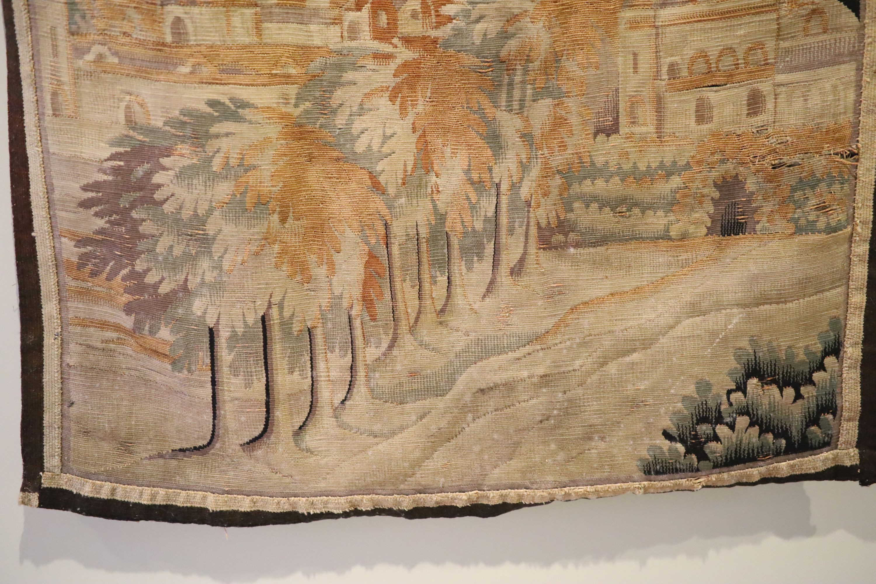 A French tapestry wall hanging, decorated with a town and trees, 125 x 79cm, with associated wrought iron hanging rail